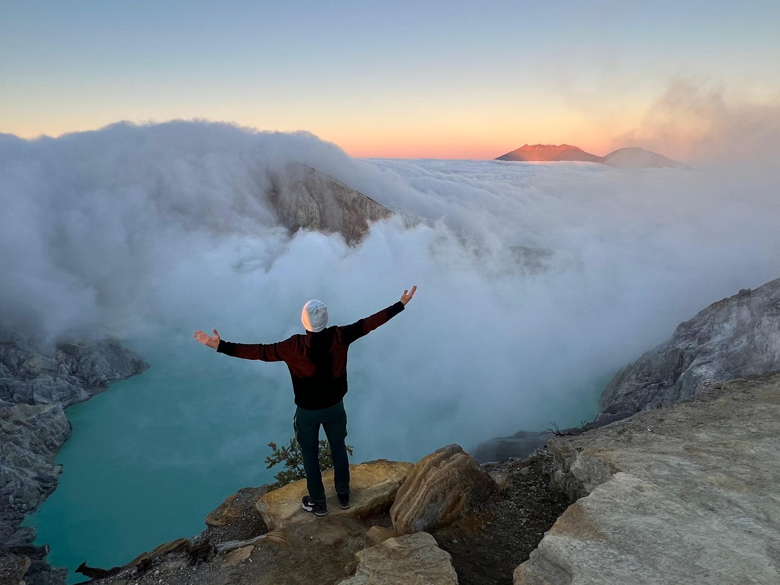 Patrick mit ausgebreiteten Armen über einem Wolkenmeer bei Sonnenaufgang
